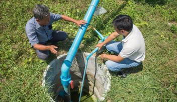 Technical staff checks biogas pipe system connecting from lagoon to power generator, May 2018, Kampong Speu province